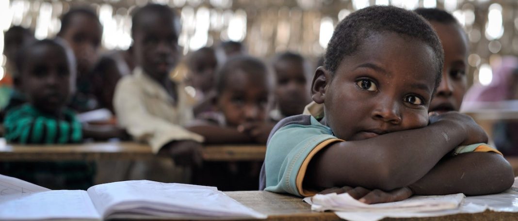 A child rests on a desk inside a crowded classroom as millions of children worldwide remain out of school