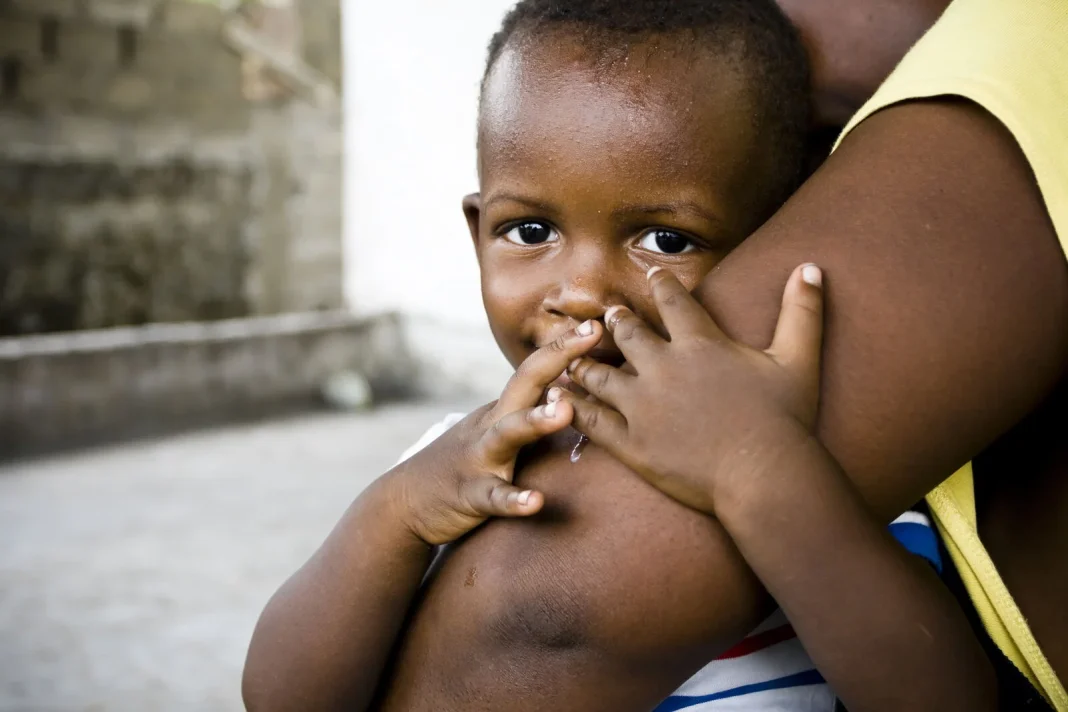 Young child resting against an adult, illustrating a story about childhood anaemia and child health