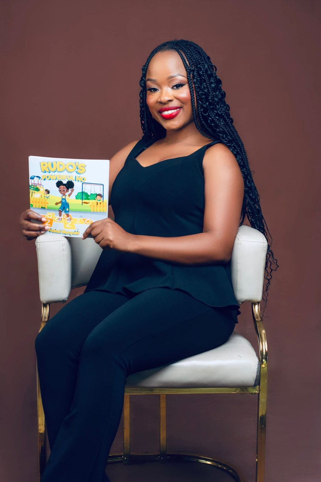 Author holds a copy of the children’s book Rudo’s Powerful No during a studio portrait.