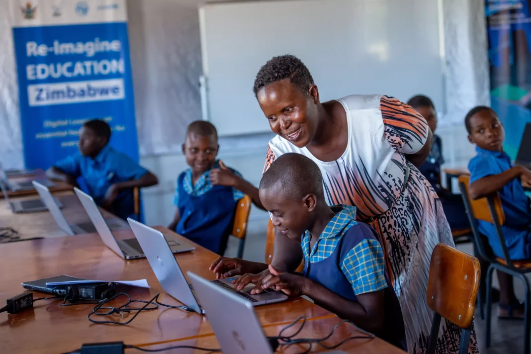 Zimbabwean schoolchildren using laptops with a teacher in a classroom, showing how digital technology supports learning