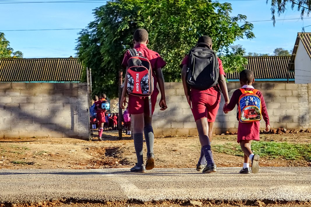 Schoolchildren in Zimbabwe walk to school with backpacks, showing the everyday realities that shape childhood in local communities.